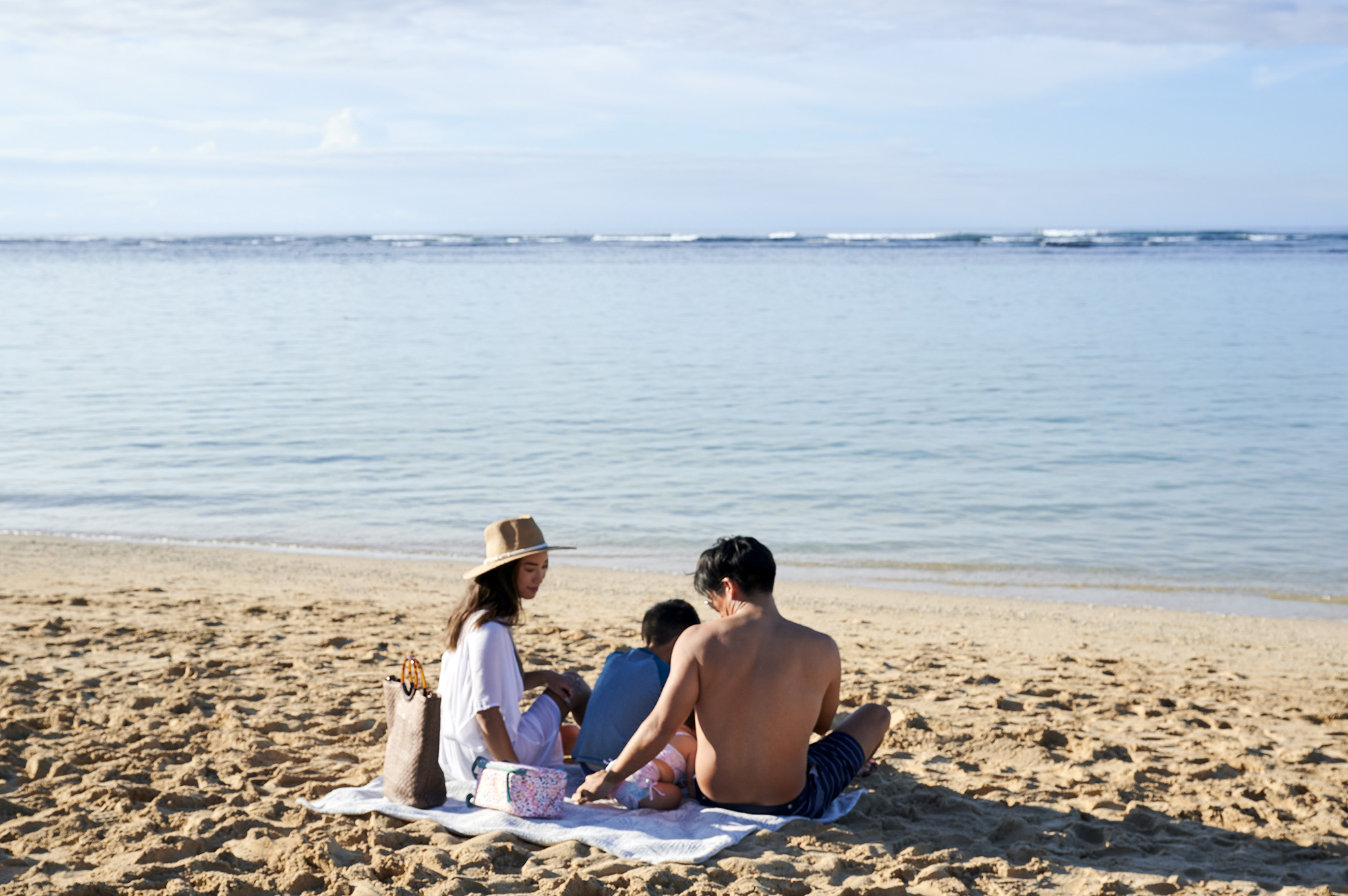 Young family sitting on the beach sand