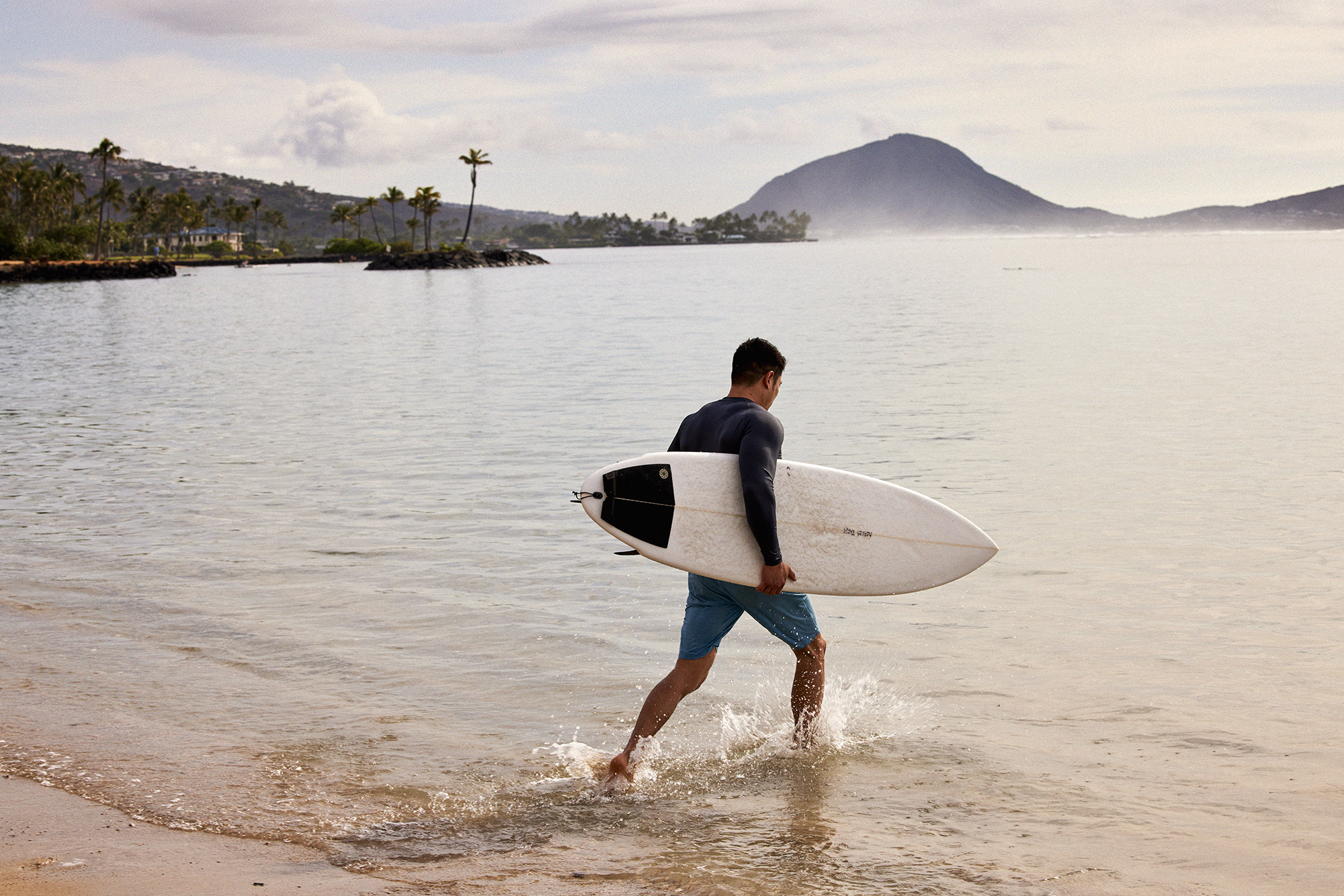 Surfer with surfboard entering the water