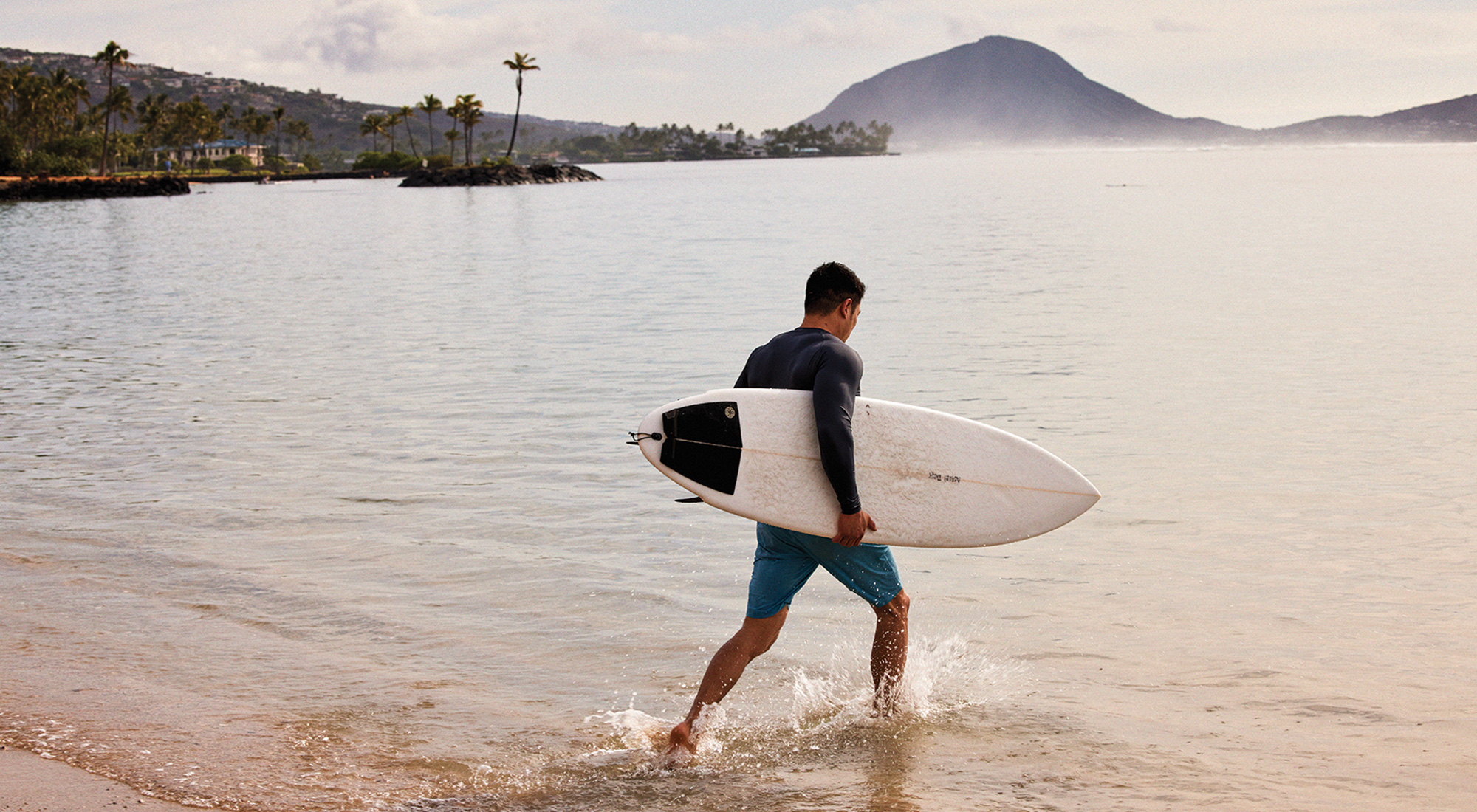 Surfer with surfboard entering the ocean